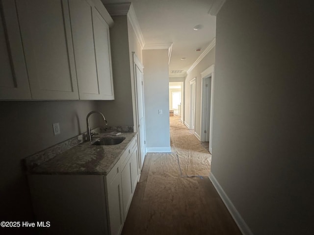 hallway featuring ornamental molding, a sink, and baseboards