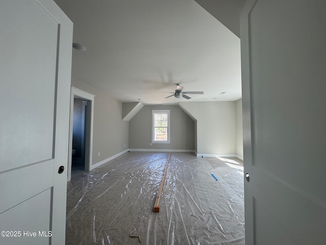 additional living space featuring vaulted ceiling, a ceiling fan, and baseboards