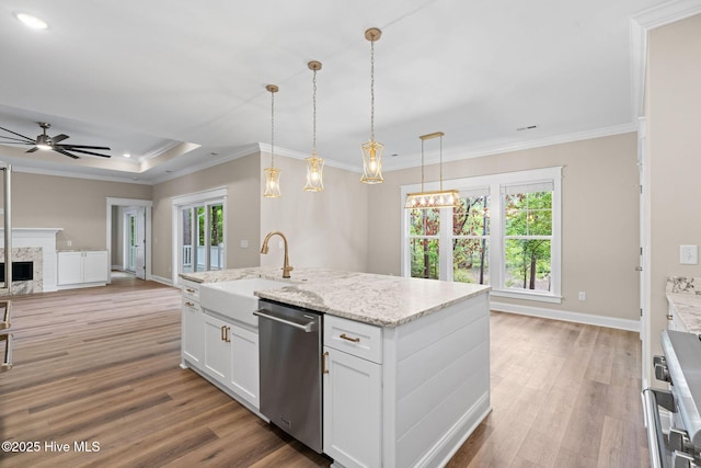 kitchen with wood finished floors, stainless steel dishwasher, ceiling fan, a sink, and open floor plan