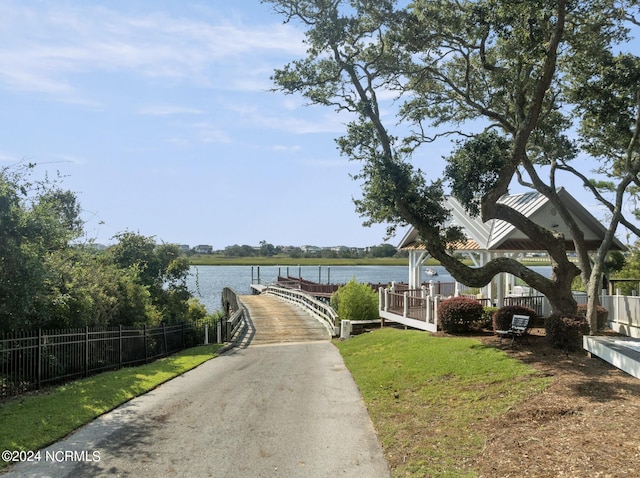 view of home's community featuring a boat dock, a water view, and fence