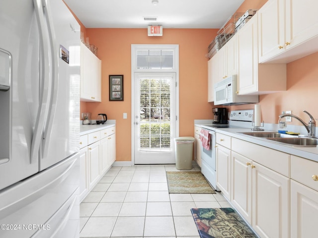 kitchen with white appliances, light countertops, white cabinetry, a sink, and light tile patterned flooring