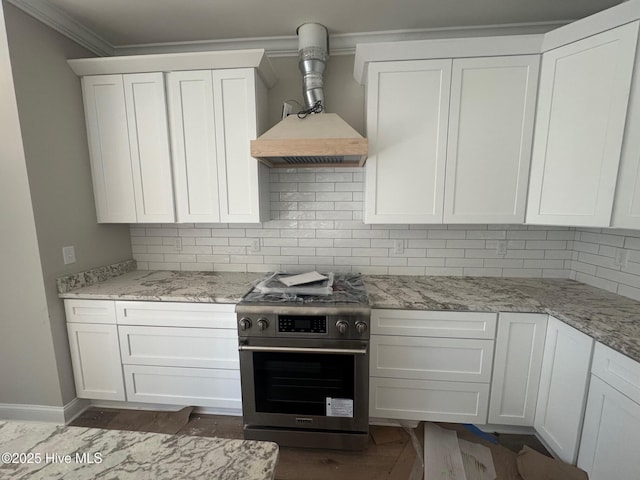 kitchen with stainless steel gas range oven, white cabinets, ornamental molding, custom exhaust hood, and backsplash