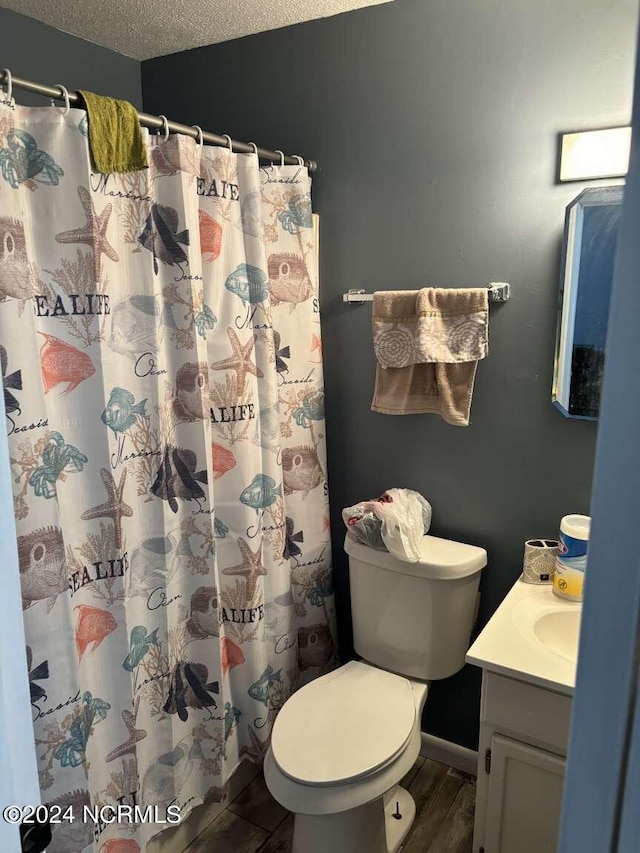 bathroom featuring toilet, hardwood / wood-style floors, vanity, a textured ceiling, and walk in shower