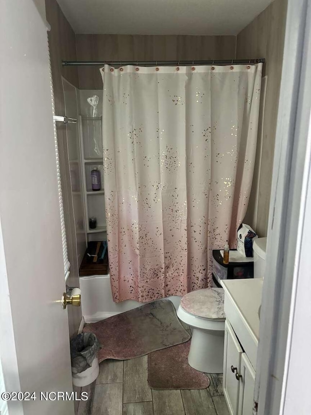 full bathroom with toilet, hardwood / wood-style floors, shower / bathtub combination with curtain, and vanity