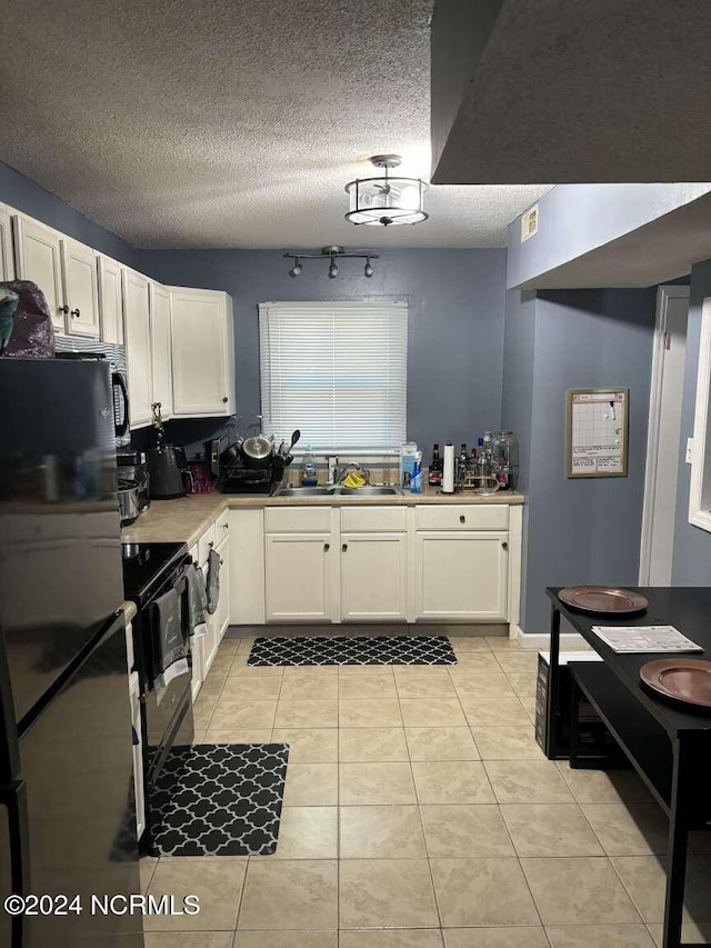 kitchen featuring black appliances, sink, light tile patterned flooring, a textured ceiling, and white cabinets