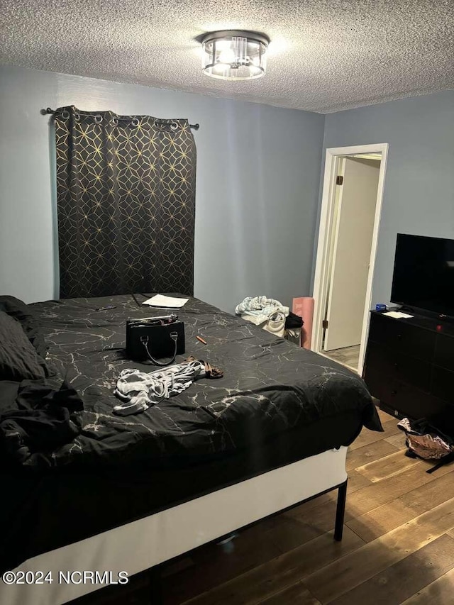 bedroom featuring hardwood / wood-style flooring and a textured ceiling