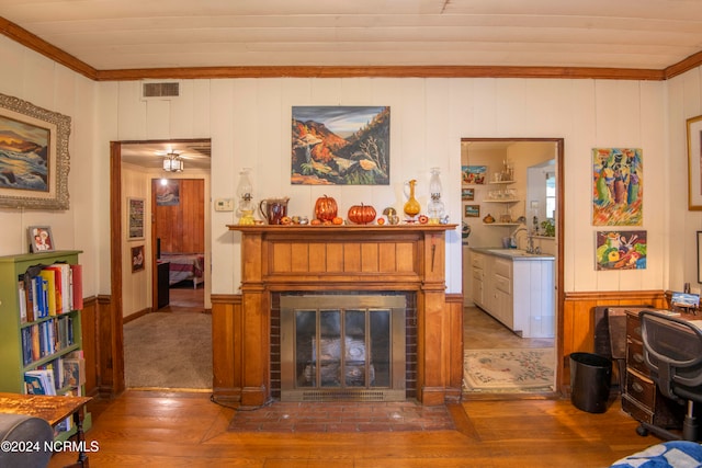 living room featuring sink, hardwood / wood-style floors, a fireplace, and ornamental molding