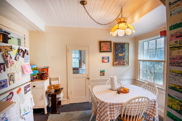 dining room with wood ceiling, ornamental molding, and dark colored carpet