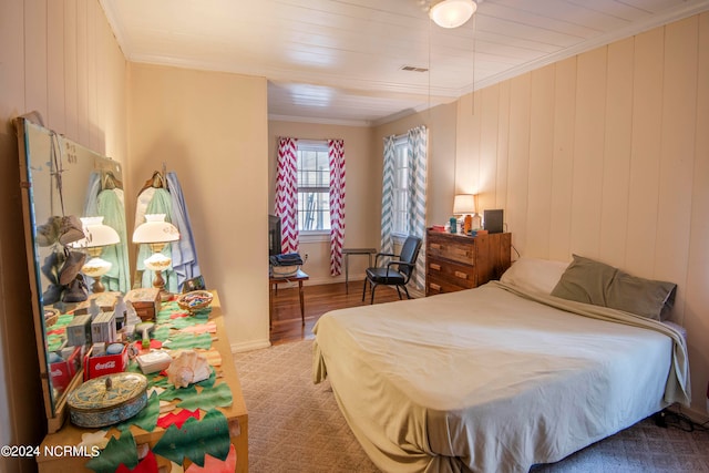 carpeted bedroom featuring crown molding and wood walls