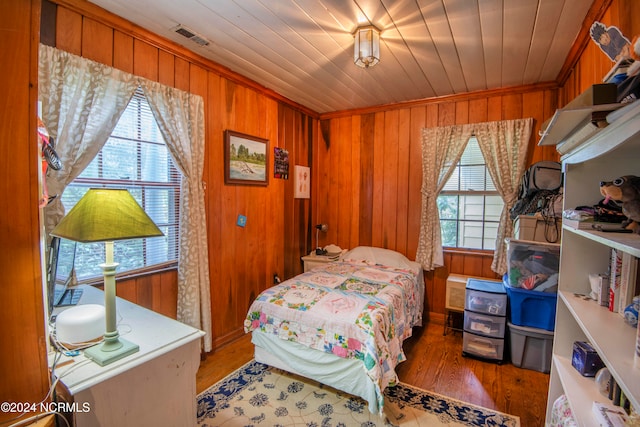 bedroom featuring multiple windows, hardwood / wood-style floors, wooden ceiling, and wood walls