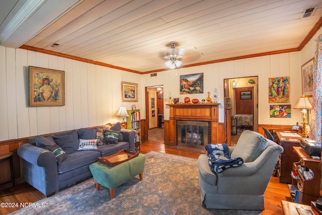 living room featuring wood walls, hardwood / wood-style floors, a brick fireplace, and ceiling fan