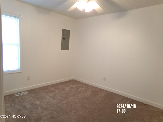 unfurnished room with ceiling fan, electric panel, and dark carpet