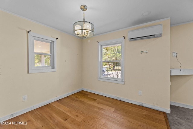 spare room with an AC wall unit, a notable chandelier, crown molding, and light hardwood / wood-style flooring