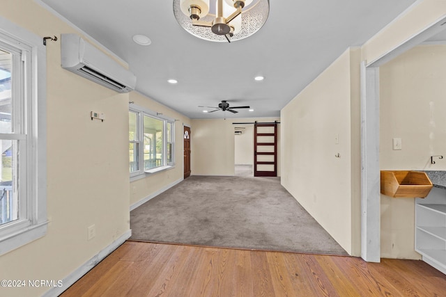 interior space featuring a barn door, a wall unit AC, a healthy amount of sunlight, and light hardwood / wood-style flooring