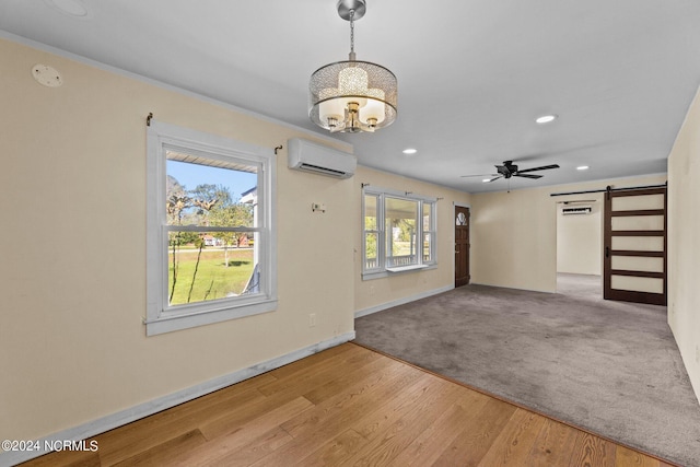 interior space featuring an AC wall unit, a barn door, ceiling fan, and light hardwood / wood-style flooring