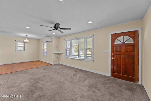 entrance foyer with ceiling fan with notable chandelier, carpet flooring, an AC wall unit, and ornamental molding