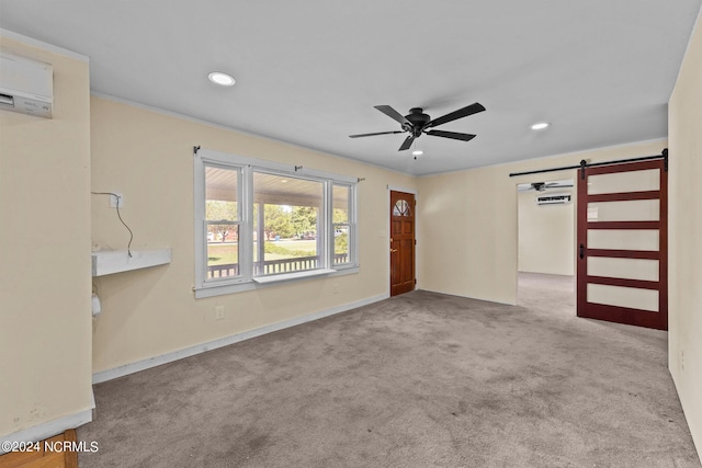 spare room featuring an AC wall unit, light carpet, a barn door, and ceiling fan