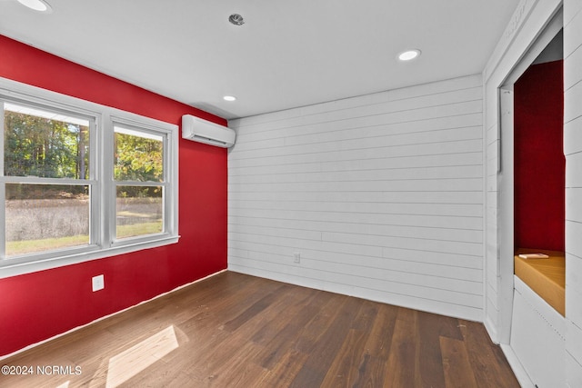 empty room with wood walls, a wall unit AC, and dark hardwood / wood-style floors