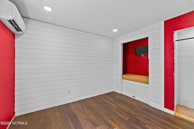 unfurnished room featuring an AC wall unit, dark hardwood / wood-style flooring, and wooden walls