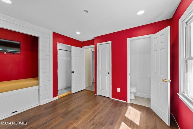 unfurnished bedroom with dark hardwood / wood-style flooring and ensuite bathroom