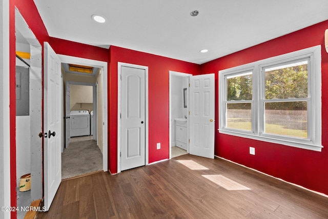 unfurnished bedroom with electric panel, independent washer and dryer, hardwood / wood-style flooring, and ensuite bathroom