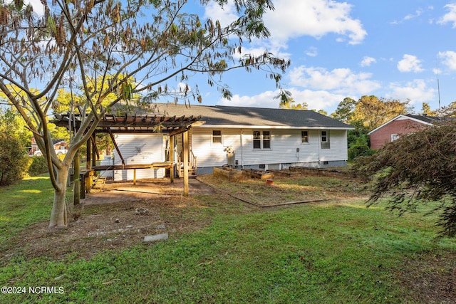 rear view of property featuring a pergola and a lawn