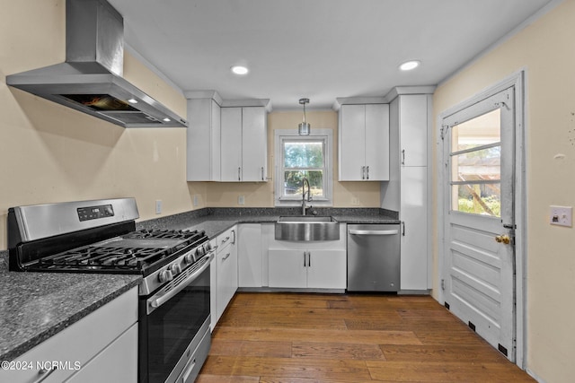 kitchen with wall chimney exhaust hood, a healthy amount of sunlight, sink, and appliances with stainless steel finishes