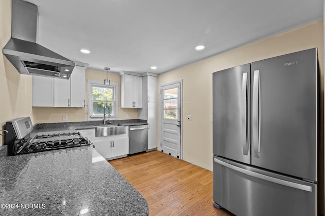 kitchen featuring light hardwood / wood-style floors, sink, wall chimney range hood, white cabinetry, and appliances with stainless steel finishes