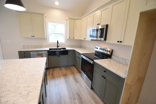 kitchen featuring lofted ceiling, appliances with stainless steel finishes, light wood-type flooring, gray cabinetry, and sink