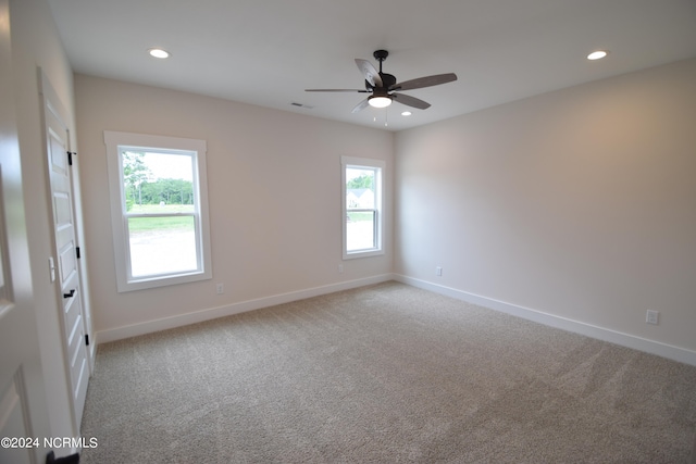 empty room with light colored carpet, a healthy amount of sunlight, and ceiling fan