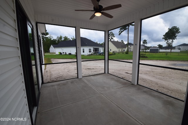 unfurnished sunroom featuring ceiling fan, wooden ceiling, and plenty of natural light