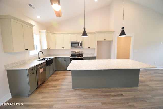 kitchen with a kitchen island, stainless steel appliances, decorative light fixtures, high vaulted ceiling, and light hardwood / wood-style flooring