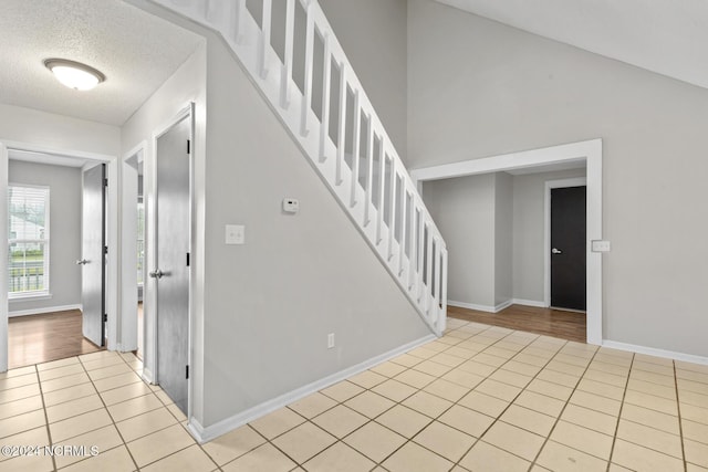 staircase featuring tile patterned flooring, a textured ceiling, and baseboards
