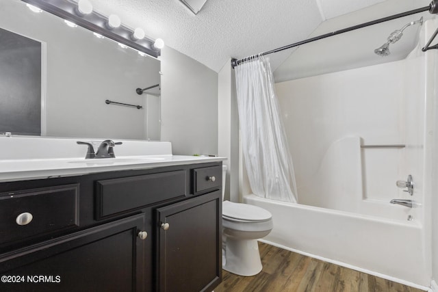bathroom featuring vanity, wood finished floors, toilet, shower / bathtub combination with curtain, and a textured ceiling