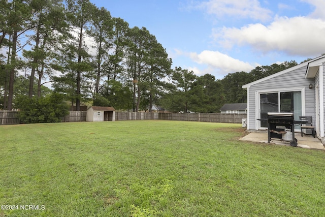 view of yard featuring a fenced backyard, an outbuilding, a shed, and a patio