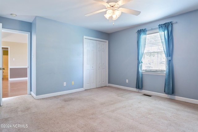 unfurnished bedroom with light carpet, a closet, and ceiling fan