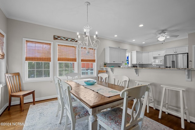 dining area featuring crown molding, dark hardwood / wood-style floors, and ceiling fan with notable chandelier