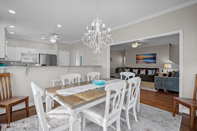 dining area with crown molding, sink, ceiling fan with notable chandelier, and hardwood / wood-style floors