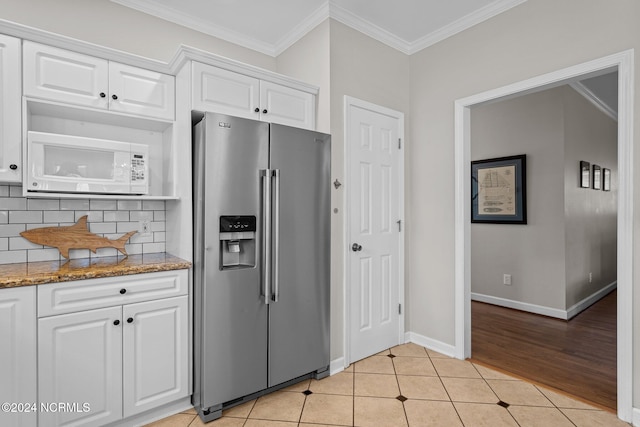 kitchen featuring decorative backsplash, stainless steel fridge, white cabinets, and stone counters