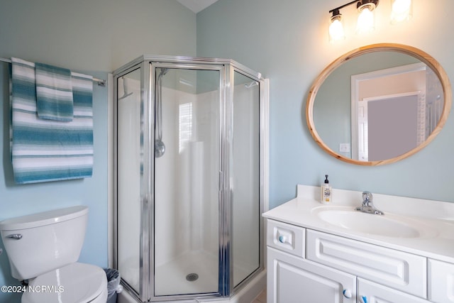 bathroom featuring vanity, toilet, and a shower with shower door