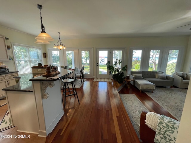 kitchen featuring white cabinets, hanging light fixtures, an inviting chandelier, a breakfast bar, and dark hardwood / wood-style floors