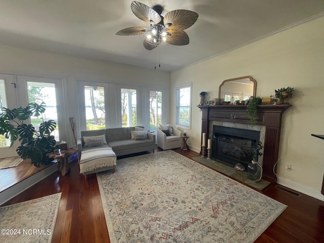 living room featuring ceiling fan, a tiled fireplace, and dark hardwood / wood-style flooring