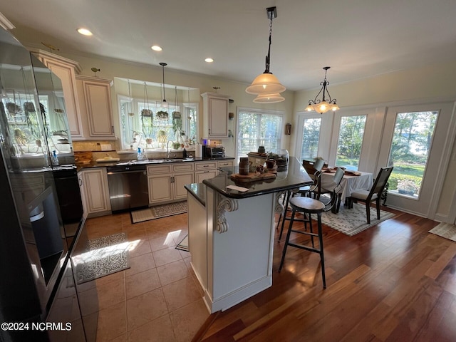 kitchen with hanging light fixtures, a kitchen bar, light wood-type flooring, dishwasher, and a center island