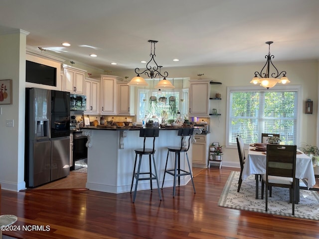 kitchen featuring dark wood-type flooring, stainless steel fridge with ice dispenser, pendant lighting, and a breakfast bar area