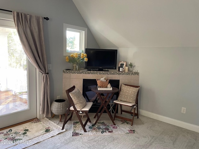 living area featuring lofted ceiling, a tile fireplace, and carpet floors