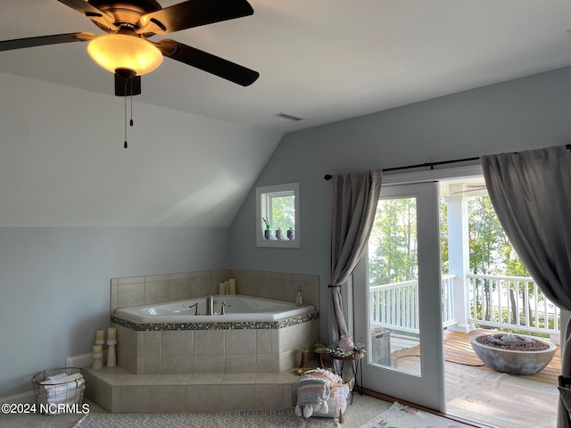 bathroom with ceiling fan, vaulted ceiling, and tiled bath