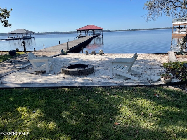 view of dock with an outdoor fire pit, a yard, and a water view