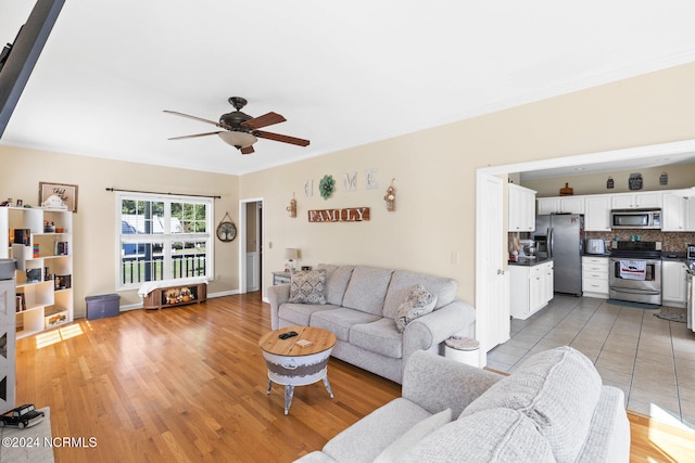 living room featuring ornamental molding, light hardwood / wood-style flooring, and ceiling fan