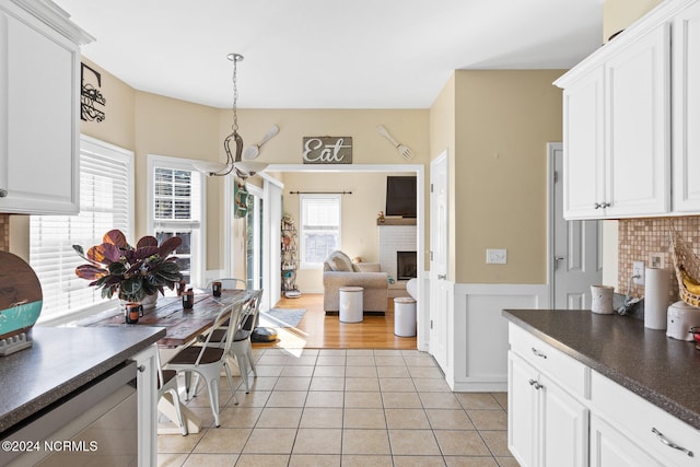 kitchen featuring light tile patterned flooring, white cabinetry, hanging light fixtures, and a healthy amount of sunlight