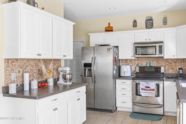 kitchen featuring white cabinets, stainless steel appliances, light tile patterned floors, and tasteful backsplash